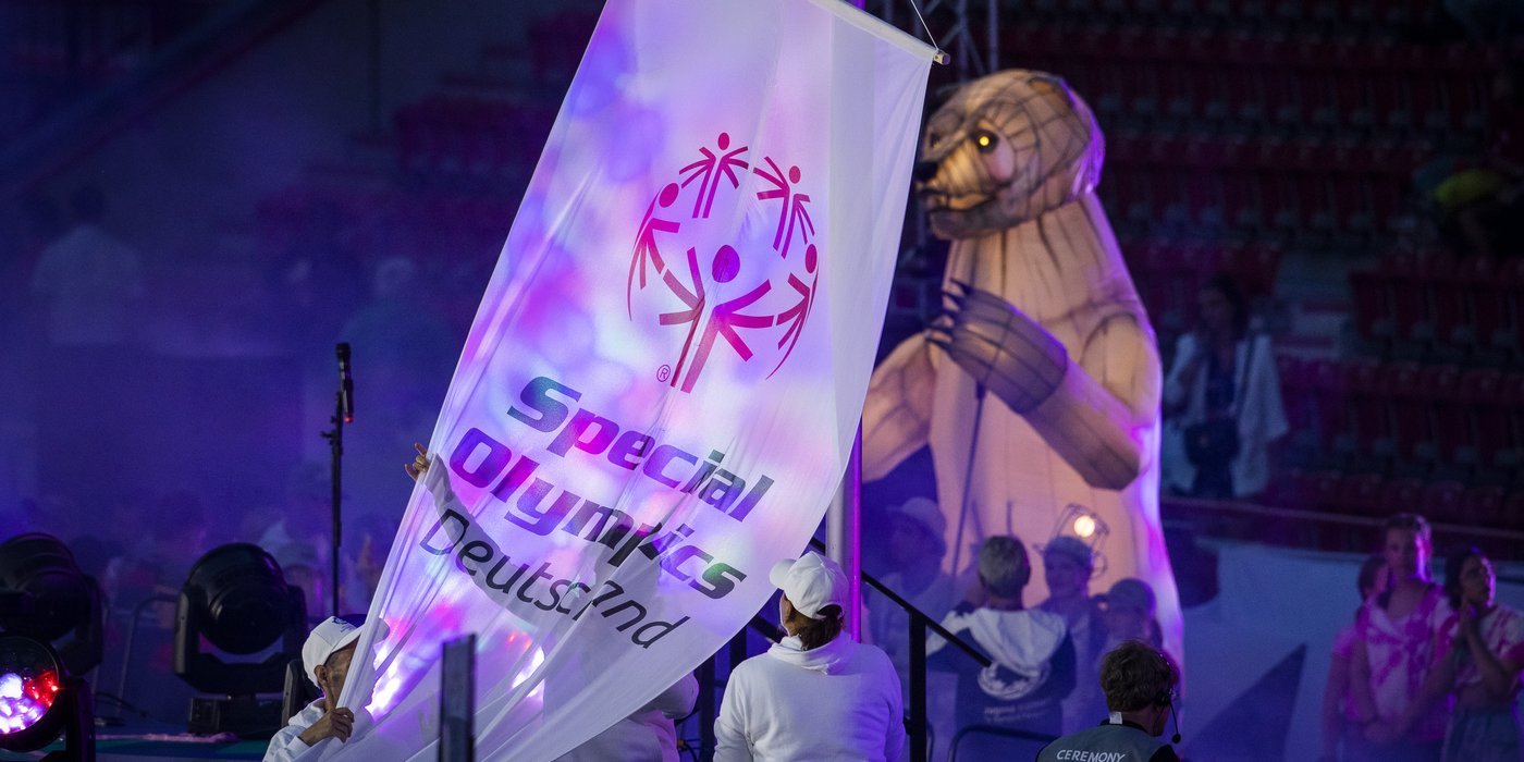 Eröffnungsfeier Nationale Sommerspiele 2022 in Berlin. Weißer Banner mit Special Olympics Deutschland Aufschrift und dem Special Olympics Logo darüber. 