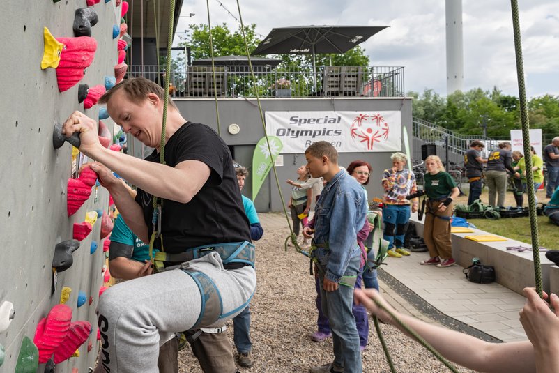 Personen klettern eine Wand hoch beim Kletter-Aktionstag von Special Olympics Bremen.