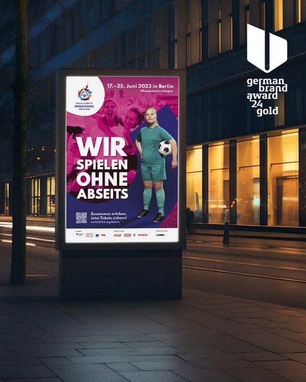 Es ist eine Werbetafel auf einer Straße zu erkennen. Auf dieser Werbetafel ist eine Fußballspielerin zu sehen. Auf der Tafel steht: "Wir spielen ohne Abseits"