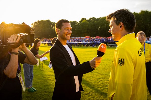Ein ZDF Reporter mit Kameramann interviewt einen Team SOD Athleten bei der Eröffnungsfeier der Weltspiele Berlin 2023